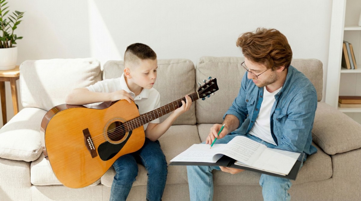 Child learning guitar with an instructor during a music class that builds concentration and discipline